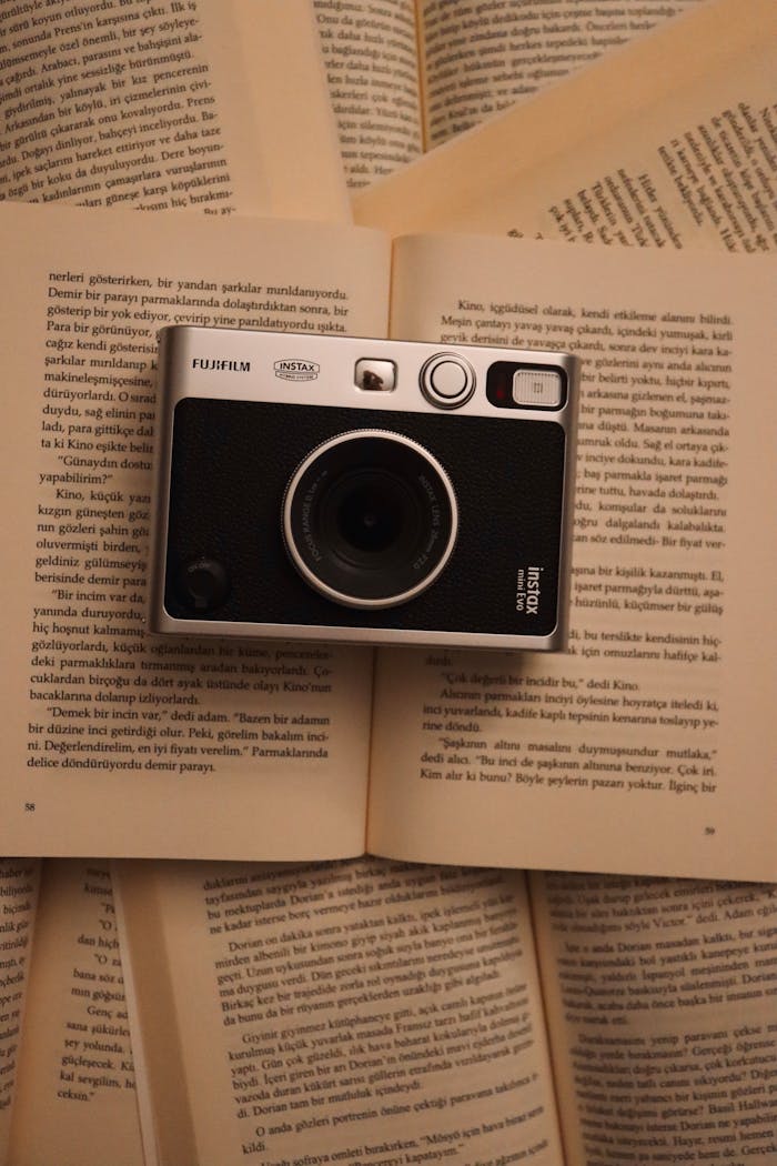 Stylish vintage instant camera placed on open book pages for an artistic touch.
